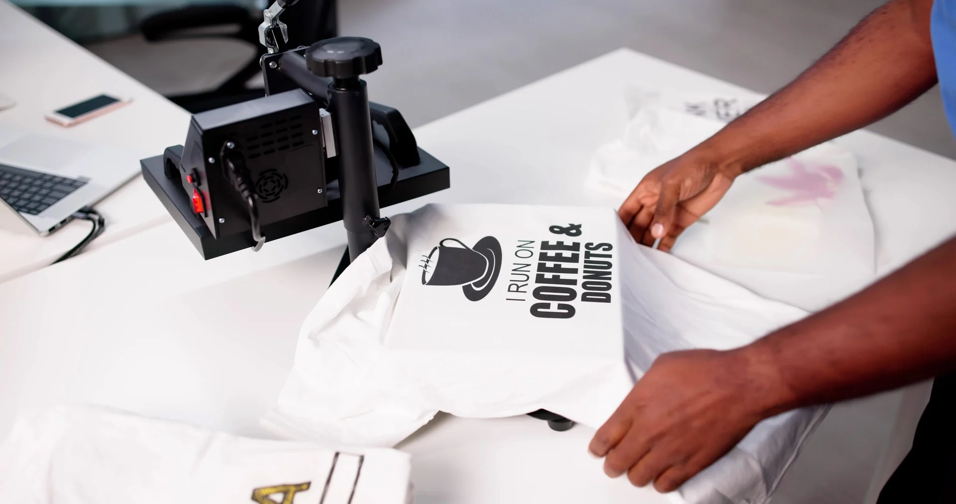 Man screen printing custom t-shirt at heat press